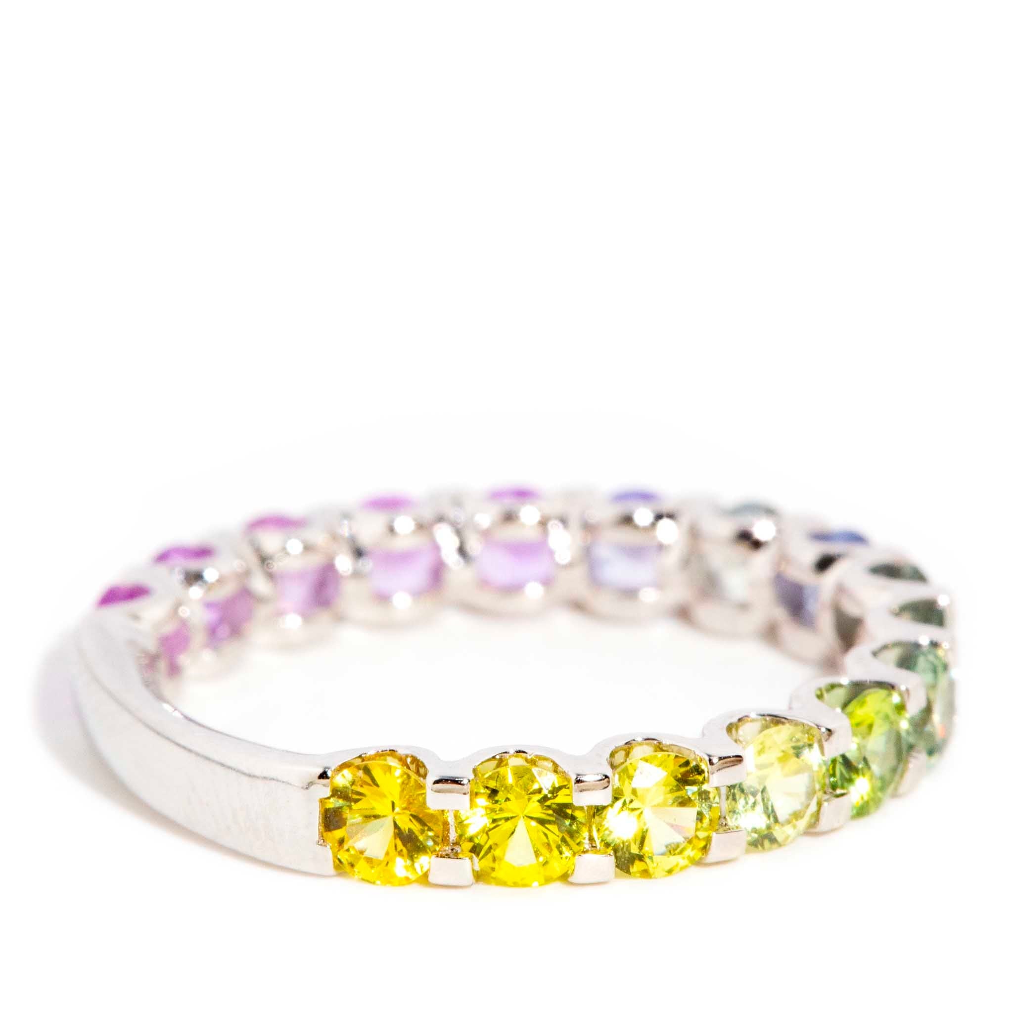 AI ALT: 18ct gold ring with ombre Ceylon sapphires in blue, pink, purple, green, and yellow, set in a sleek band design.